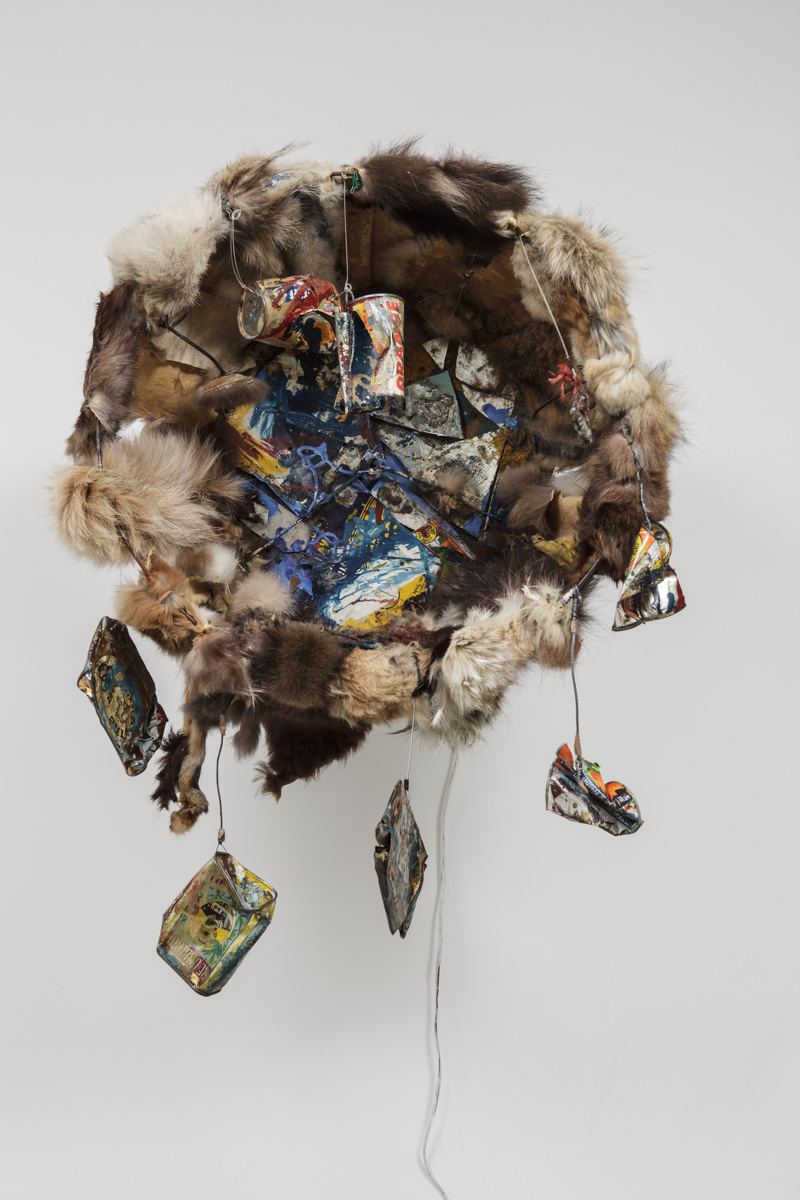 circular installation made of fur with cans, paint, and other multimedia/assemblage elements in the center or hanging from the structure