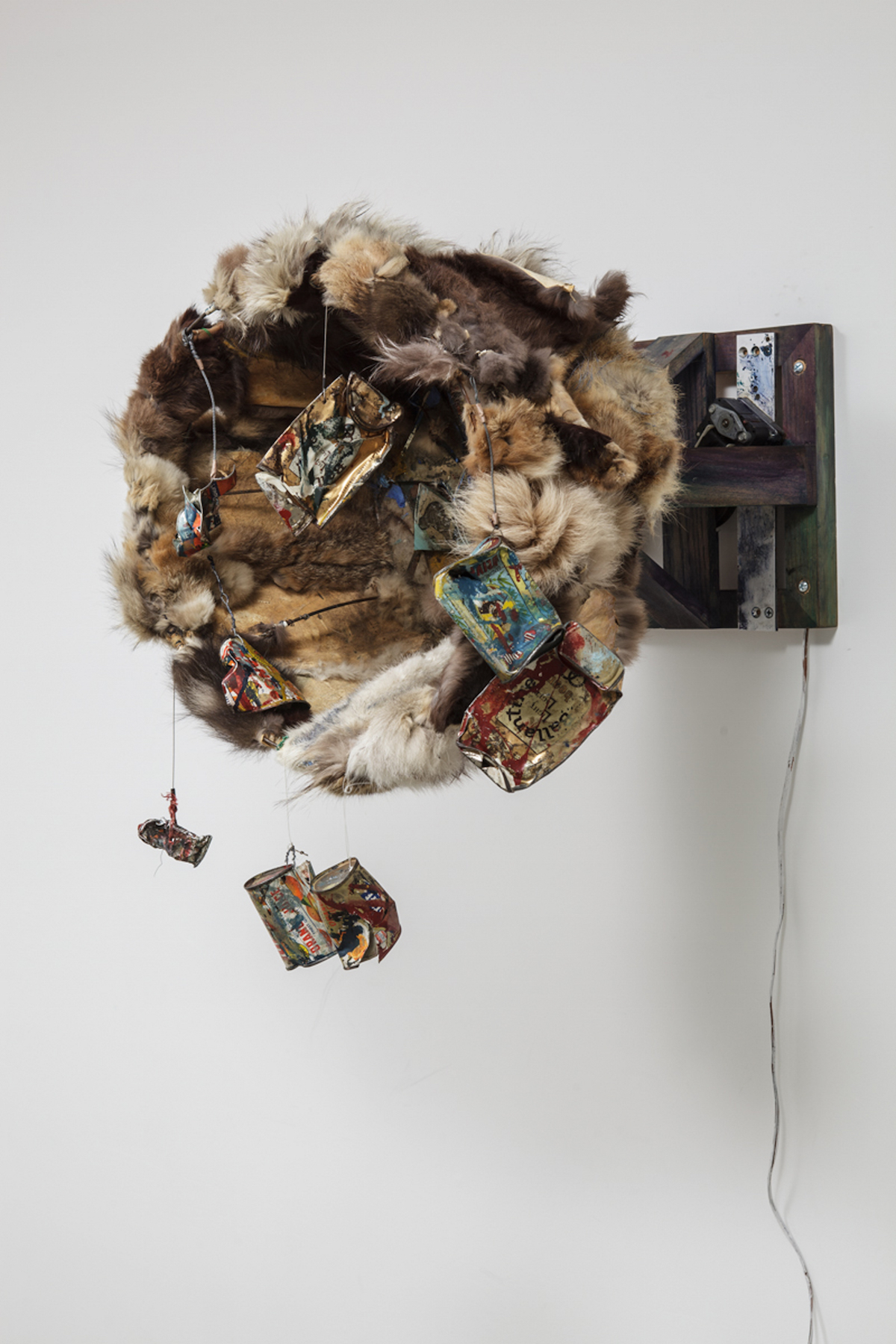 circular installation made of fur with cans, paint, and other multimedia/assemblage elements in the center or hanging from the structure