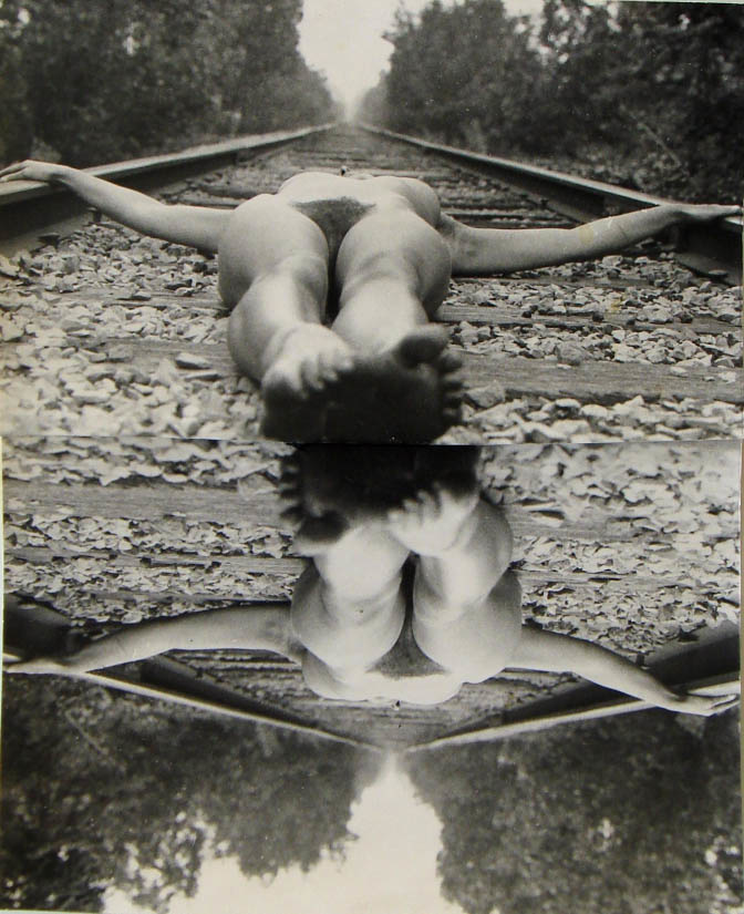 image of the artist laying nude on train tracks; the shot is taken parallel from the artist with a foreshortened view of her feet and legs