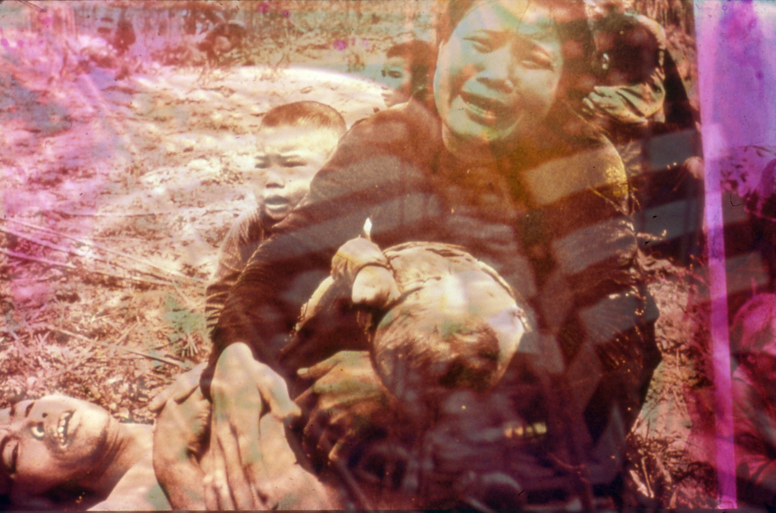 still of several figures crying: one is lying down, another looks directly at the camera, behind them there is a small boy; overlaying the image is a pink filter which abstracts the shot