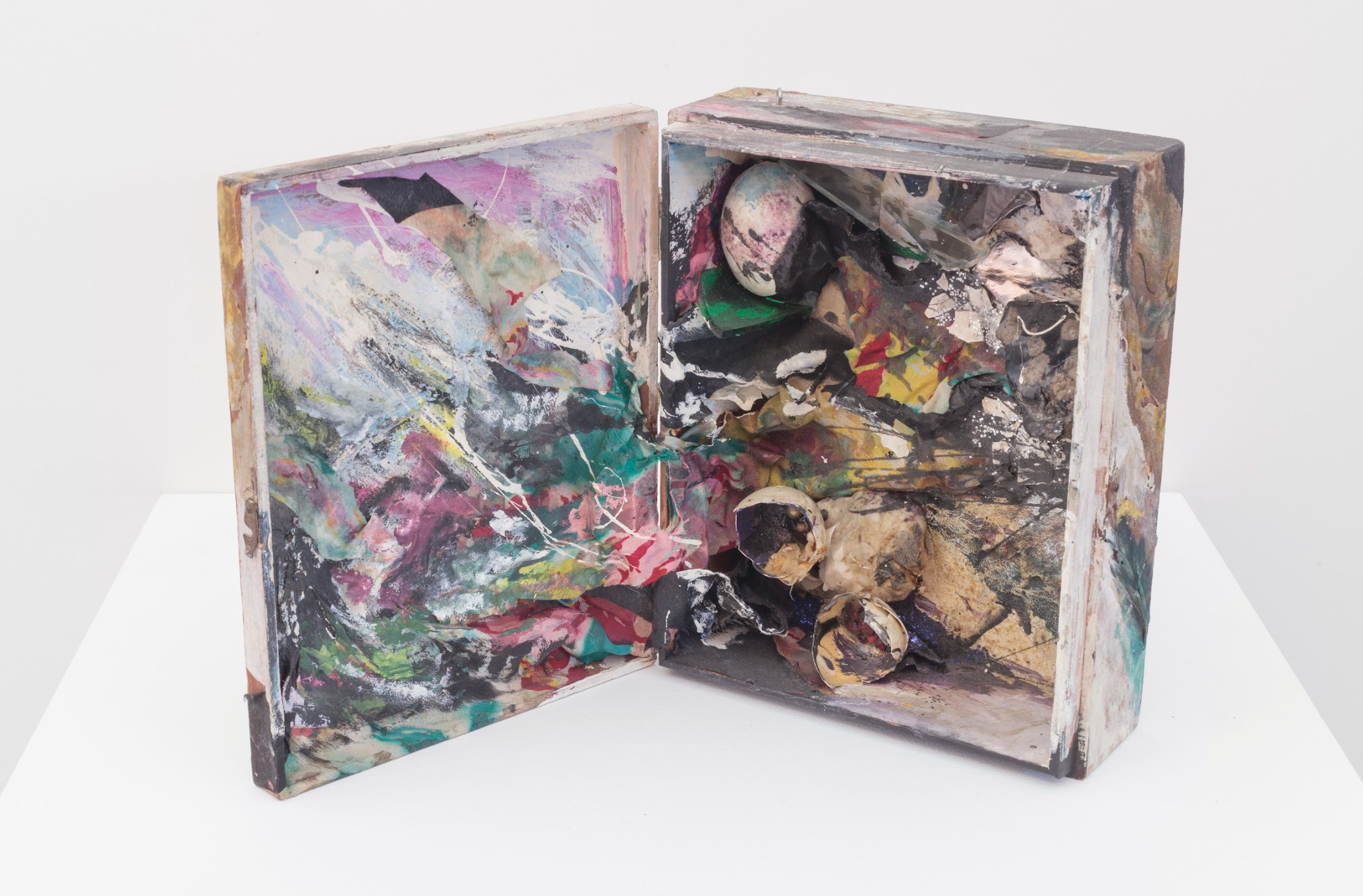 open wooden box filled with egg shells, broken glass, beads, glitter, and paint splatters